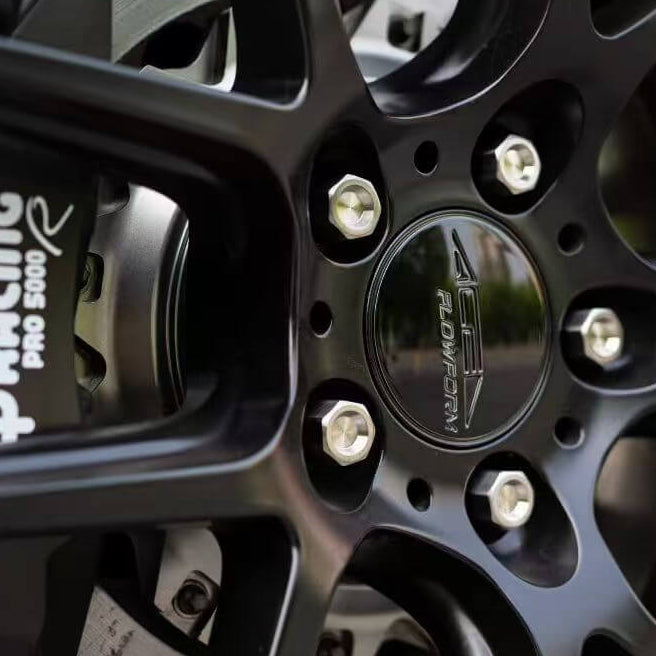 Close-up of a black alloy wheel with 'AP Racing' branding, after the installation of titanium wheel lug bolts