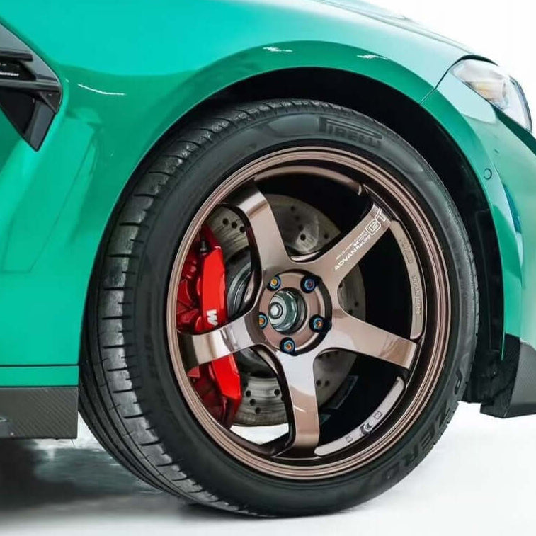 Close-up of a green bmw wheel with a detailed rim on a white background, after the installation of blue titanium wheel lug bolts