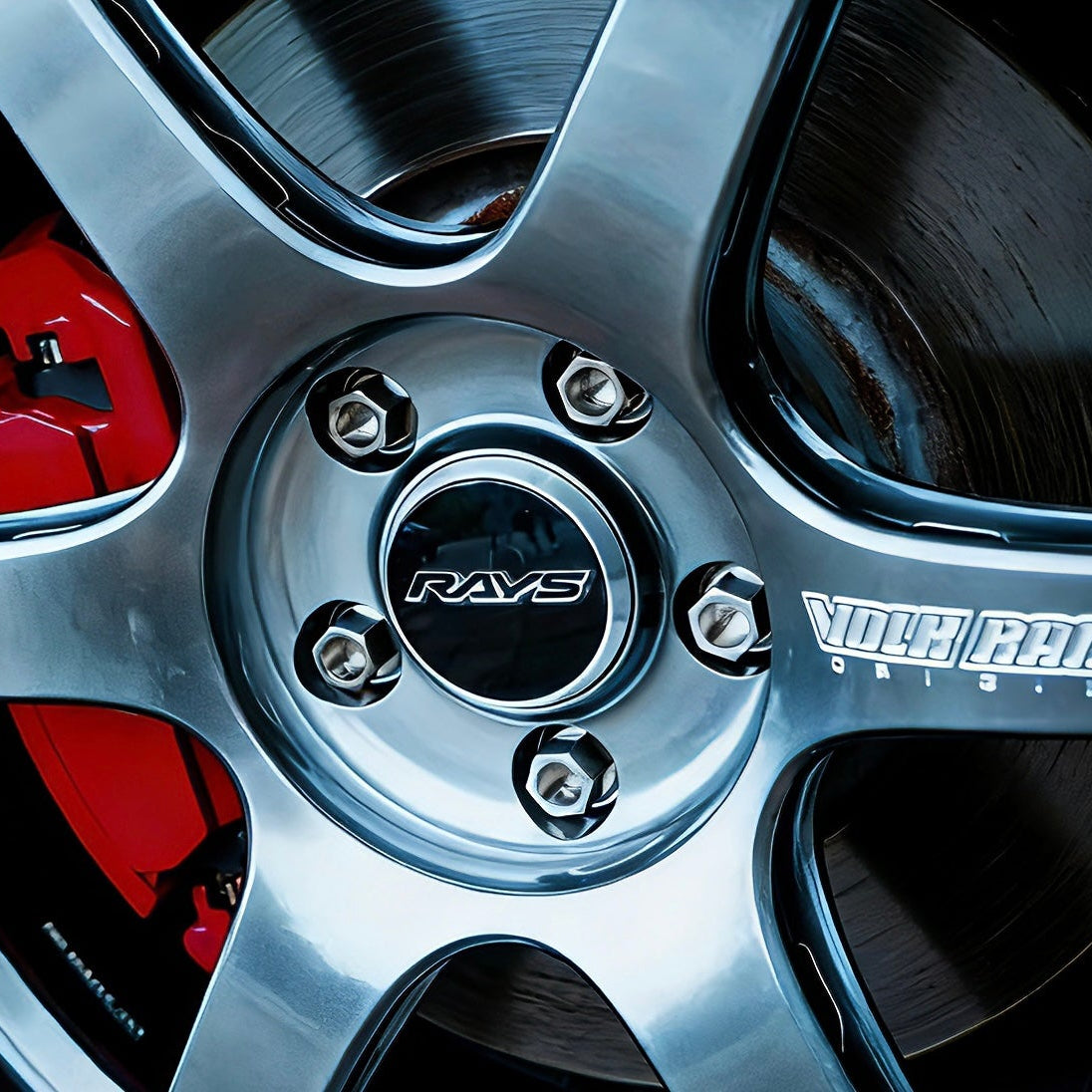 Close-up of a car wheel with a silver rim and red brake caliper, featuring 'RAYS' and 'Yokohama' branding. fit titanium wheel lug bolts competition series