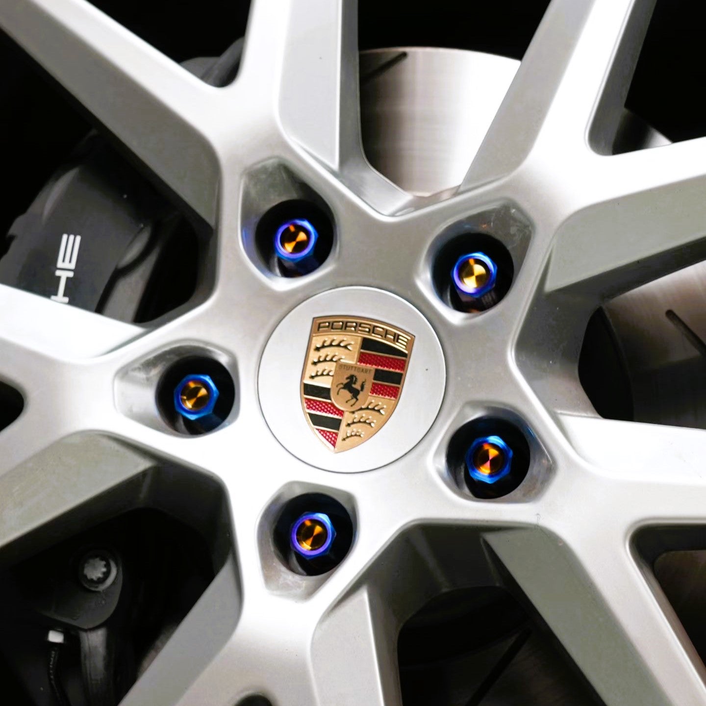 Close-up of a Porsche car wheel with the blue titanium wheel lug bolts customer feedback